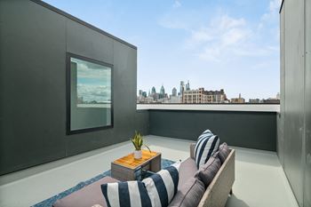 A balcony with a striped couch and a table with a vase of flowers.
